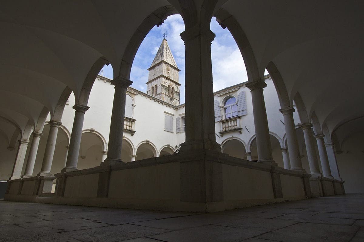 A courtyard with arches and a clock tower.