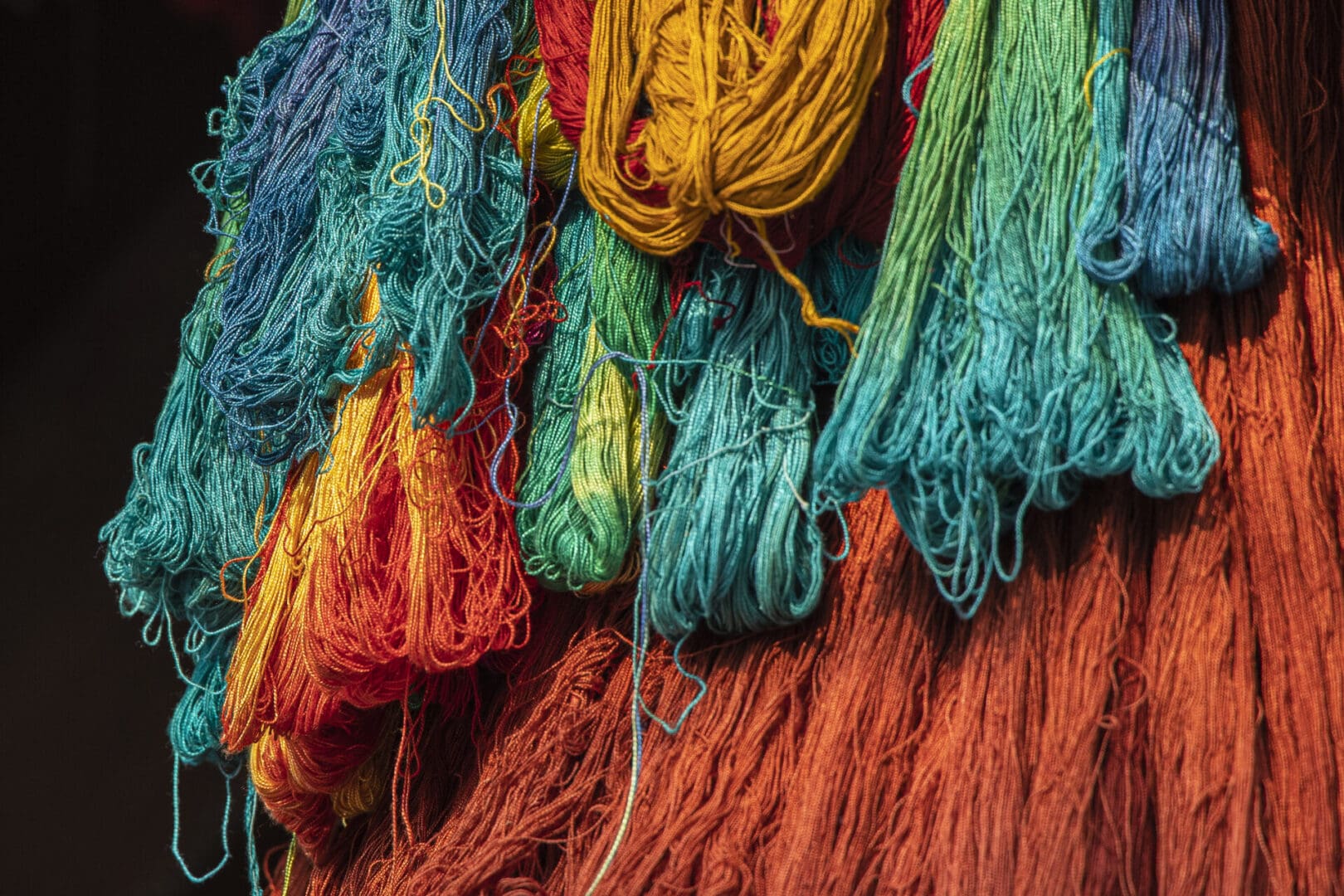 A close up of colorful yarn hanging on a wall.