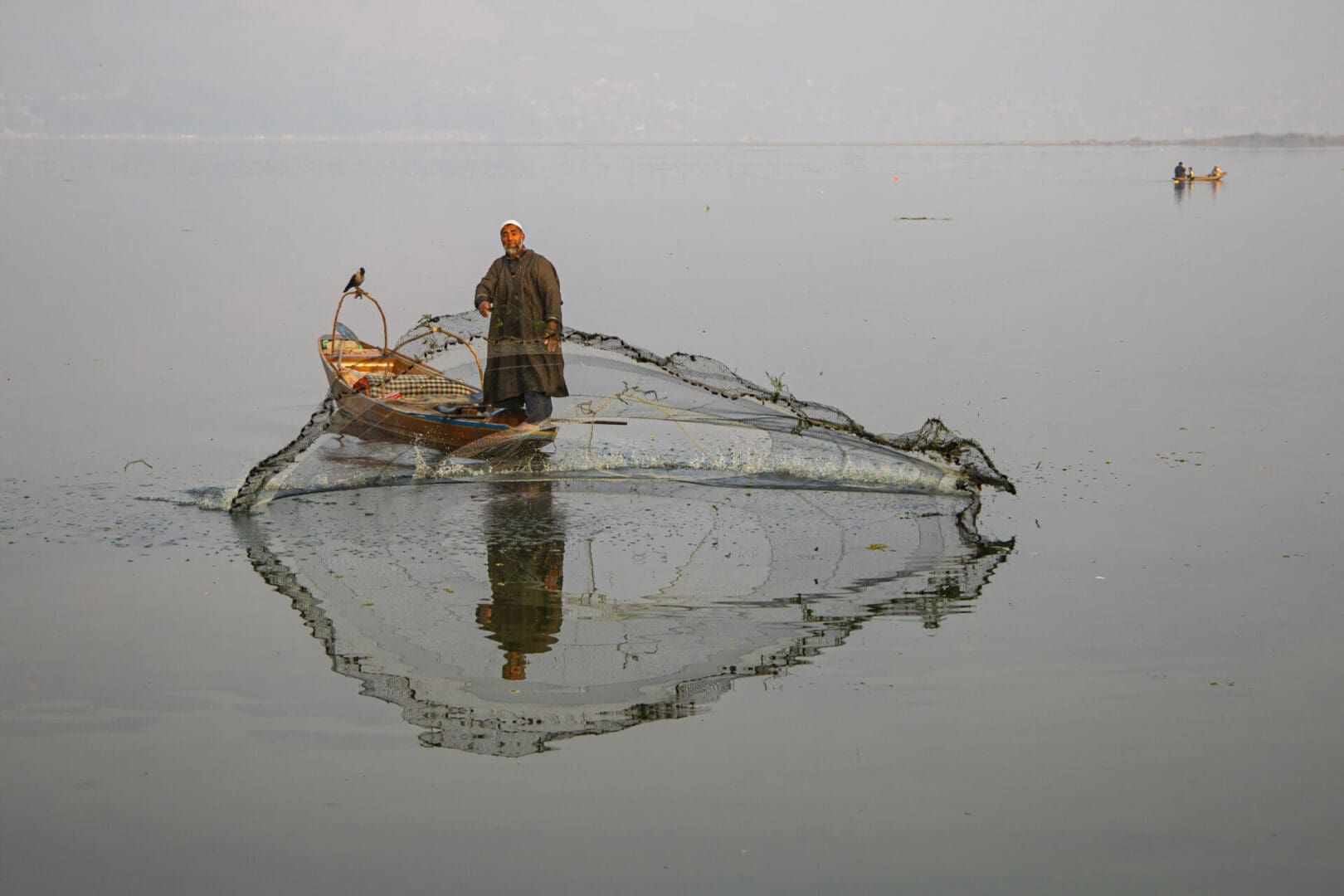 A man is fishing in a boat on a lake.