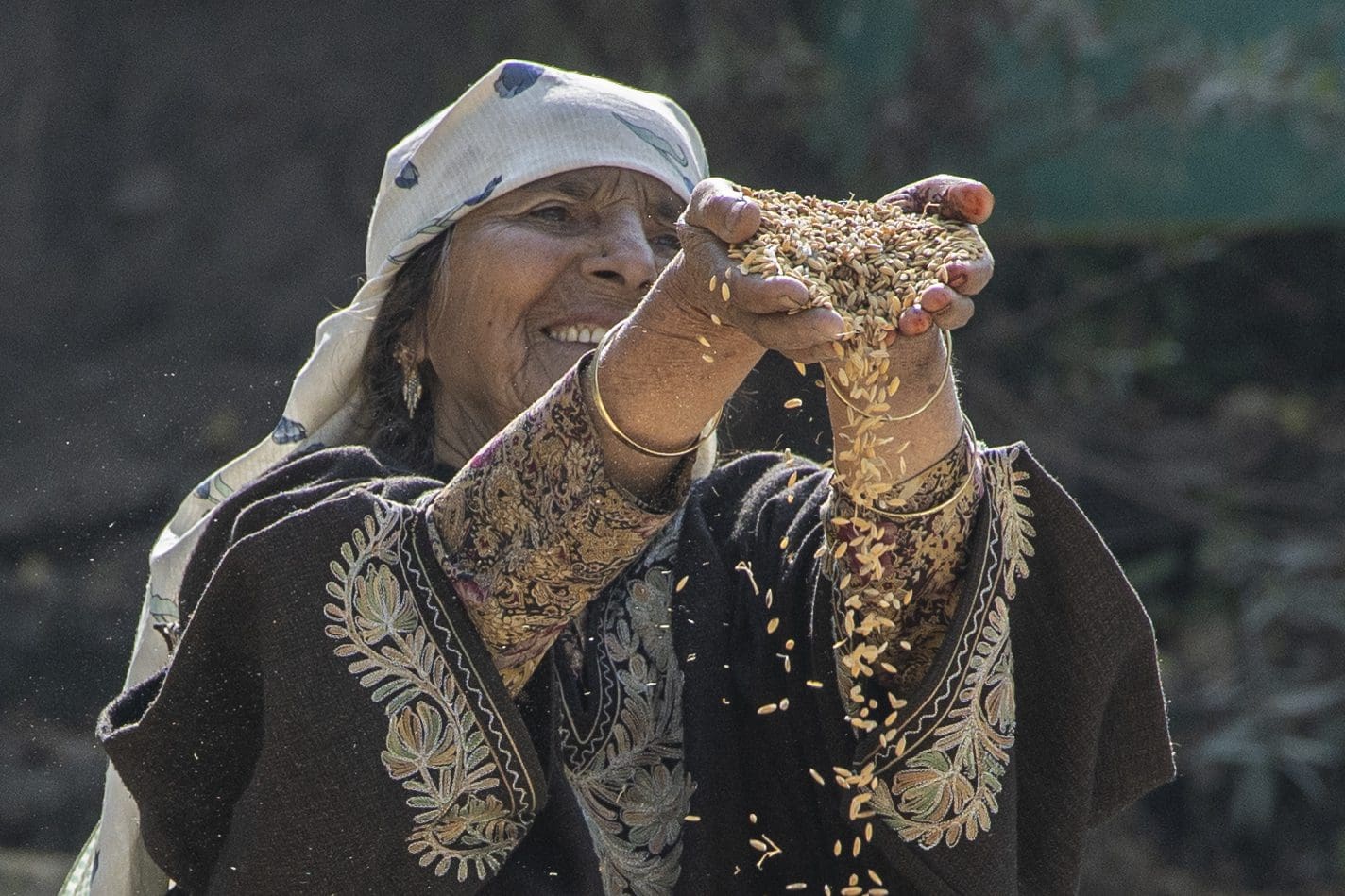 A woman is holding a handful of grain in her hand.