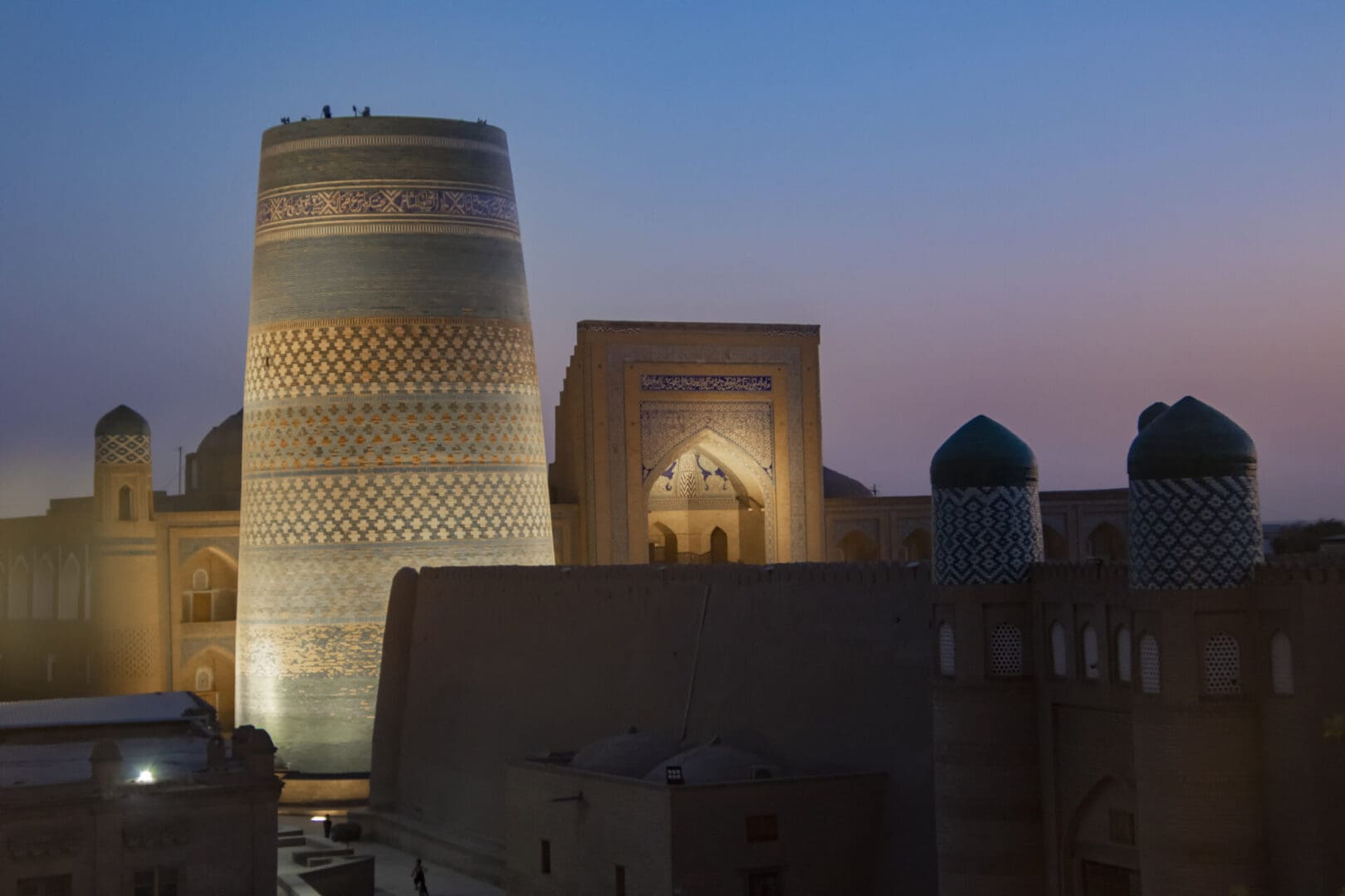 A mosque is lit up at dusk in uzbekistan.