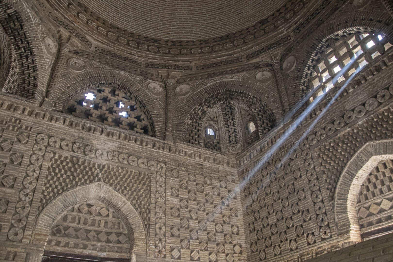 The inside of an ornate building with a light shining through the windows.