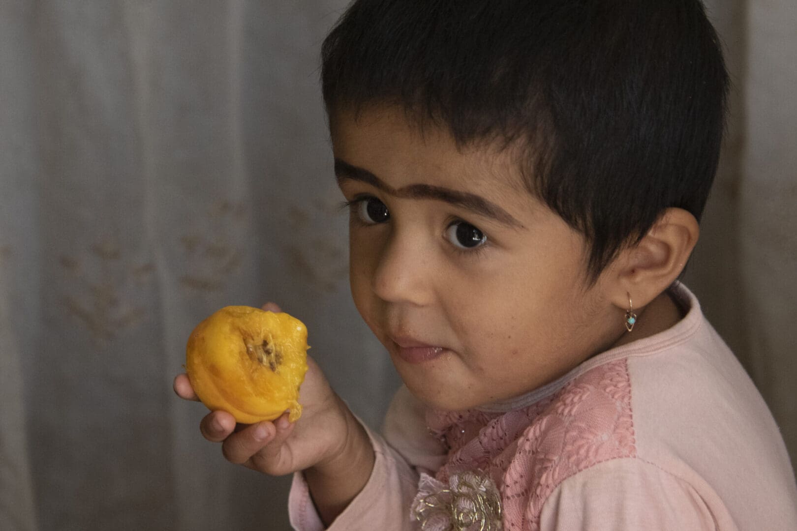 A child is eating a piece of fruit.
