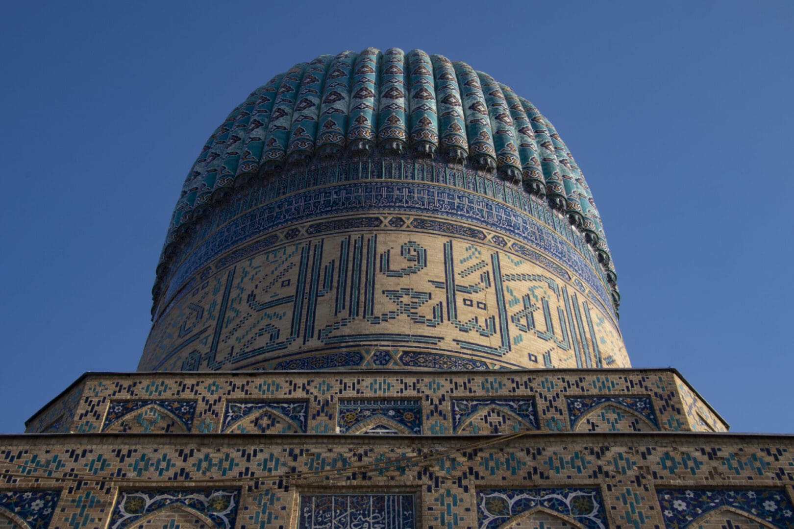 The dome of a mosque with a blue sky behind it.